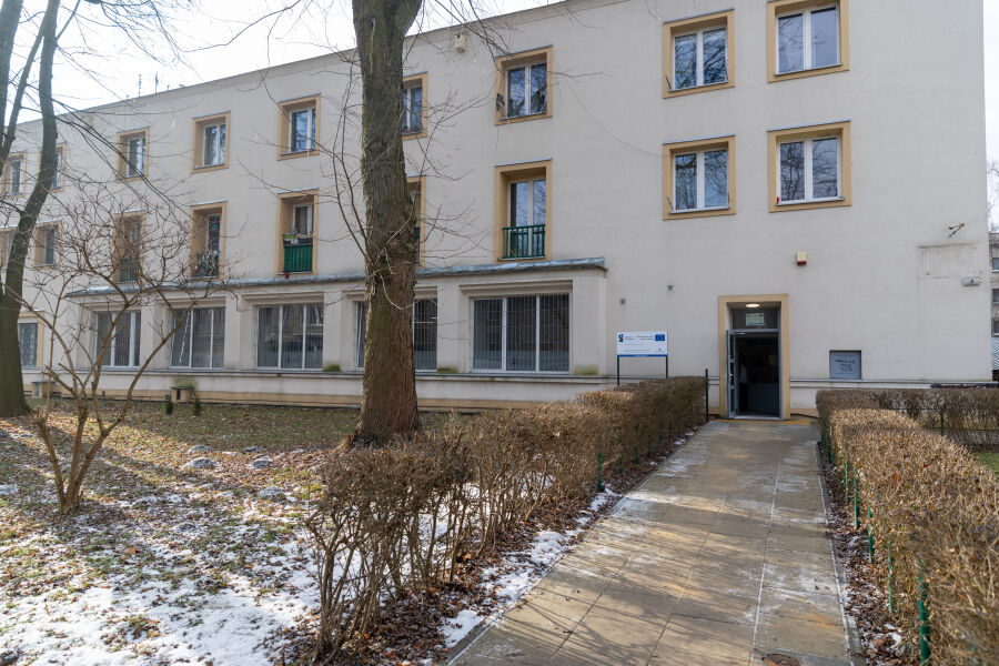 Budynek nowo otwartego Centrum dla Rodzin na Os. Krakowiaków 2. Widoczna fasada białego budynku, chodnik, drzewa oraz śnieg.