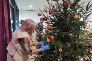 Na zdjęciu Mieszkanka zawiesza bombkę na choinkę