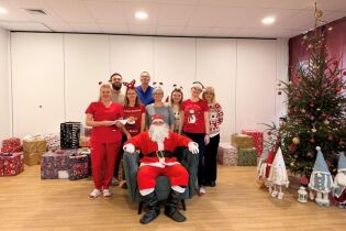 Na zdjęciu ekipa św. Mikołaja na tle prezentów, choinki oraz krasnali. Autor zdjęcia