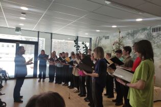 Na zdjęciu Chór Szkół Sióstr Prezentek w Krakowie wraz z dyrygentem Panem Maciejem Rutkowskim występuje przed Mieszkańcami w dniu urodzin (ujęcie z profilu).