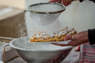 Grafika przedstawia upieczone ciastka posypywane cukrem pudrem.