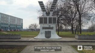 Widać pomnik Solidarności „Bądź wierny, idź” w Nowej Hucie. Biały kamień w kształcie V z tabliczkami upamiętniającymi wali o wolność.