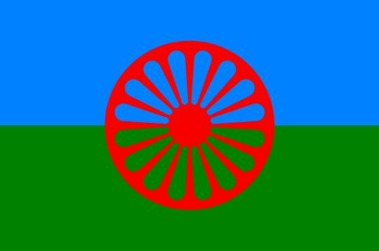 Flaga Romska. Dwa pasy niebieski symbolizujący duchowość i niebo i zielony symbolizujący ziemię a pośrodku motyw czerwonego koła indyjskiej czakry.  