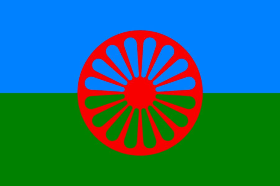 Flaga Romska. Dwa pasy niebieski symbolizujący duchowość i niebo i zielony symbolizujący ziemię a pośrodku motyw czerwonego koła indyjskiej czakry.  