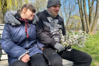 Uczestnicy uśmiechający się na ławce, z bukietem w ręce 