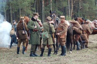 Grafika przedstawia grupę osób podczas rekonstrukcji historycznej.