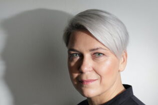 portret fotograficzny litewskiej poetki Laimy Kreivytė. Kobieta o zielonych oczach i platynowych krótko obciętych włosach z grzywką opadającą lekko na czoło