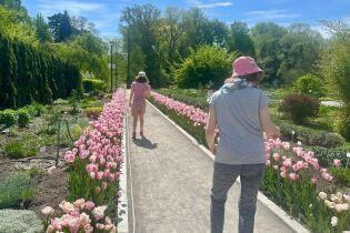 Uczestniczki spacerują wzdłuż alejki z kwiatami