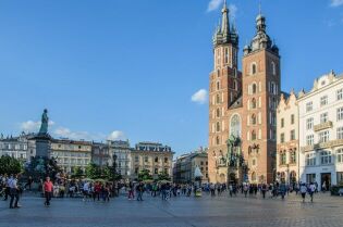 Grafika przedstawia Rynek Krakowski ze spacerującymi turystami. W tle widac Kościół Mariacki. 