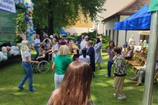 Uczestnicy wydarzenia, w tym mieszkańcy, pracownicy i goście, wspólnie tańczą oraz bawią się w ogrodzie przy scenie podczas Święta Rodzin na Krakowskiej.
