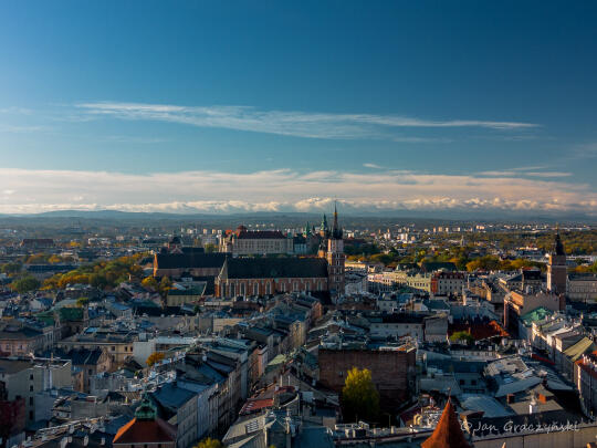 View of Kraków from above. Clear blue sky and historic buildings are visible on the ground. 