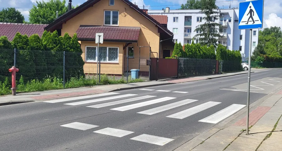 Dom przy ulicy z przejściem dla pieszych i hydrantem.
