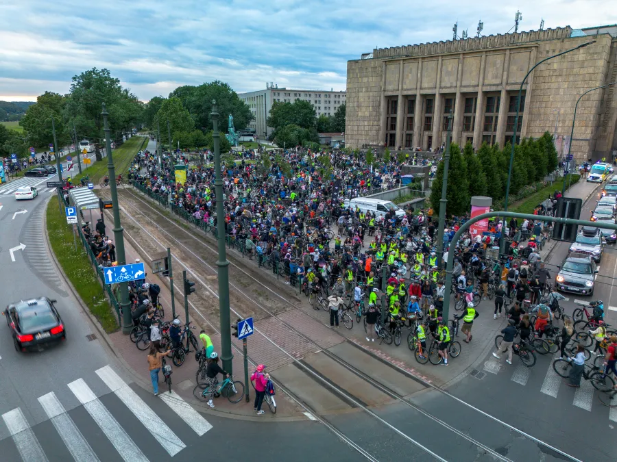 Tłum rowerzystów zgromadzony przed budynkiem Muzeum Narodowego w Krakowie. Zdjęcie wykonano przy świetle dziennym.