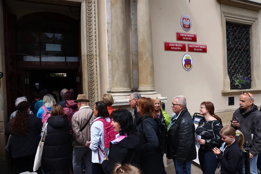 Ludzie stoją w kolejce przed budynkiem urzędowym.