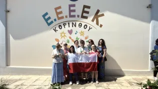 Grupa osób trzymająca flagę Polski przed kolorowym muralem z napisem E.E.E.E.K. Kopinóy.