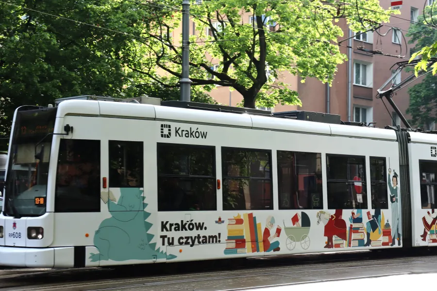 Tramwaj w Krakowie z kolorową reklamą promującą czytelnictwo.