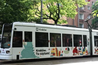 Tramwaj w Krakowie z kolorową reklamą promującą czytelnictwo.