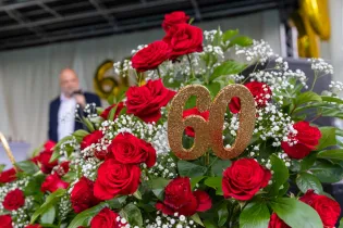 Bukiet czerwonych róż z cyfrą 60 w złotym kolorze.