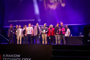 Grupa ludzi na scenie podczas ceremonii wręczenia nagród w Krakowie.