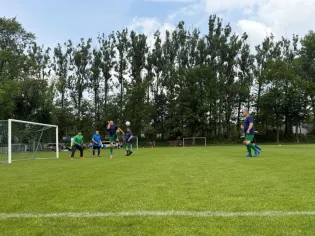 Mecz piłki nożnej na trawiastym boisku, zawodnicy w akcji.