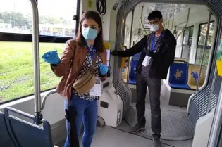 Osoby w maseczkach i rękawiczkach w tramwaju, przygotowujące się do przeprowadzenia testów sanitarnych.