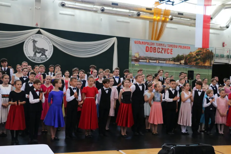 Grupa dzieci i młodzieży w strojach balowych podczas turnieju tańca.