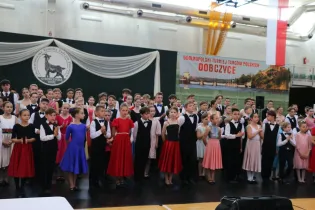 Grupa dzieci i młodzieży w strojach balowych podczas turnieju tańca.