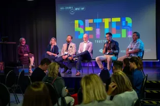 Panel dyskusyjny z sześcioma osobami na scenie, z kolorowym napisem Better Together w tle.