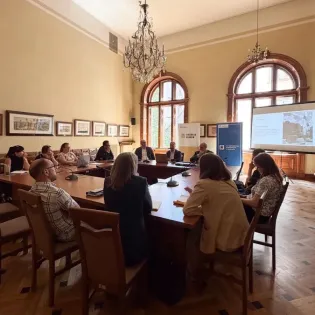 Spotkanie w sali konferencyjnej z uczestnikami i prelegentami przy stole.