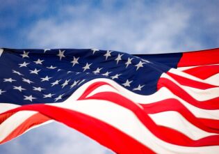 sfotografowana od dołu duża łopocąca flaga USA na tle nieba   