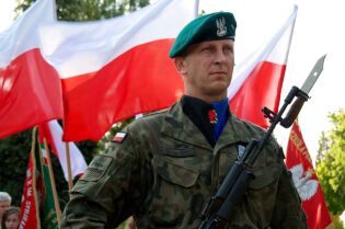 Grafika przedstawia żołnierza na tle polskiej flagi.
