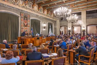 Sala obrad z radnymi, stołami i dekoracjami, w trakcie sesji.