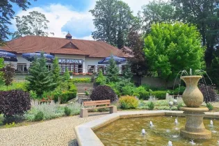 Restauracja z tarasem, fontanna i zadbany ogród.