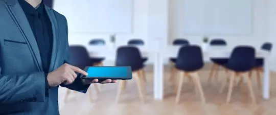 Mężczyzna w garniturze trzyma tablet w nowoczesnym biurze.