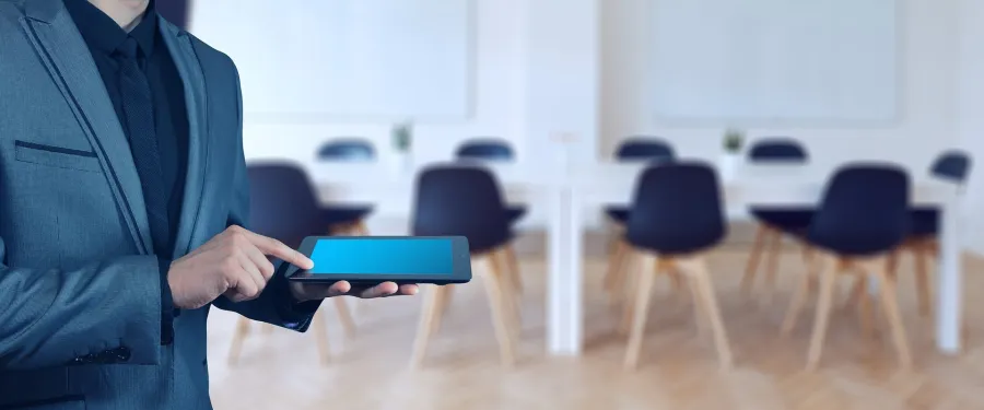 Mężczyzna w garniturze trzyma tablet w nowoczesnym biurze.