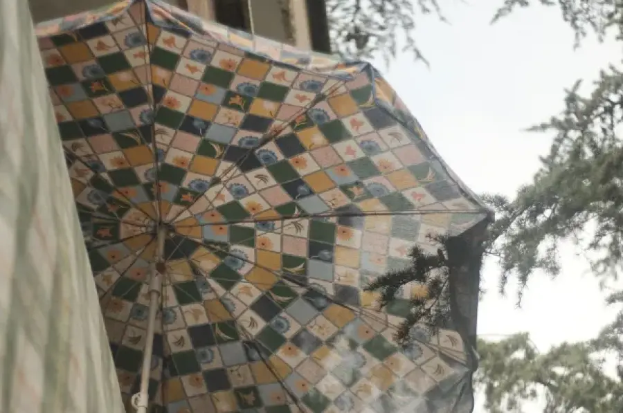 Kolorowy parasol z wzorem w kratkę wiszący nad balkonem.