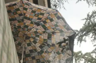 Kolorowy parasol z wzorem w kratkę wiszący nad balkonem.