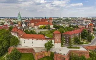 Wawel z zamkiem królewskim i zielonymi wzgórzami w tle.