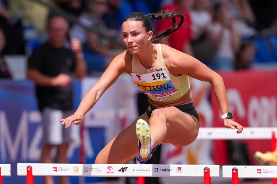 Kobieta skacząca przez płotek na zawodach lekkoatletycznych.