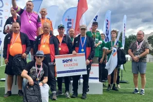 Grupa sportowców na podium z medalami, trzymających tabliczkę z napisem Kraków.