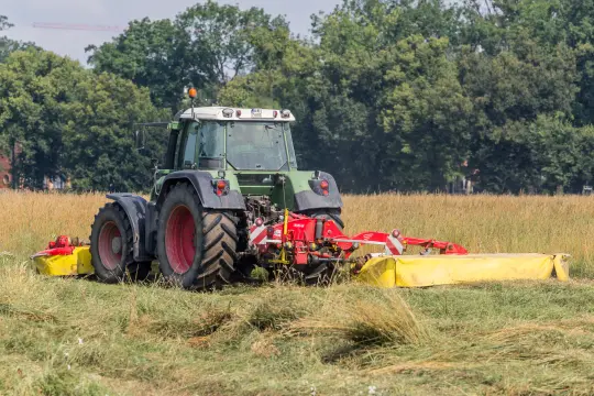Traktor koszący trawę na polu.