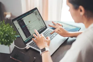 Kobieta pracująca na laptopie, korzystająca z aplikacji na biurku.