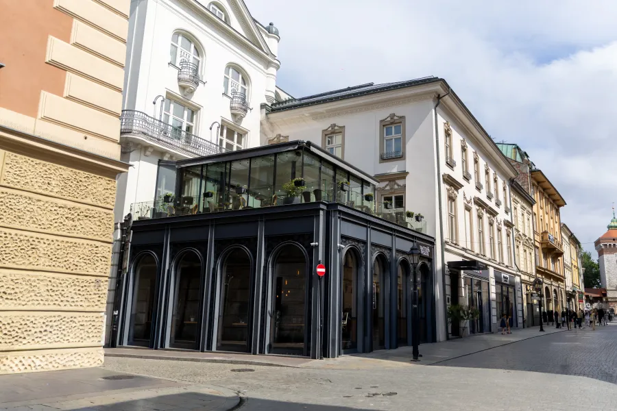 Nowoczesna kamienica z przeszklonym tarasem w miejskiej scenerii.