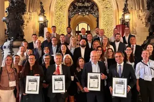 Grupa ludzi z certyfikatami w eleganckim wnętrzu budynku.