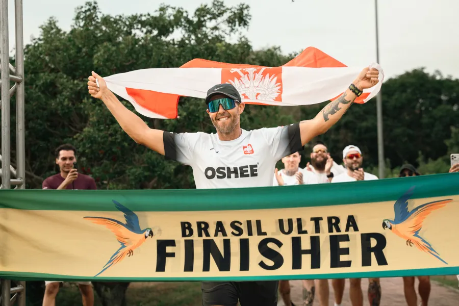 Biegacz z flagą Polski świętuje ukończenie zawodów Brasil Ultra.