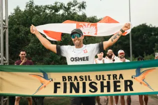Biegacz z flagą Polski świętuje ukończenie zawodów Brasil Ultra.