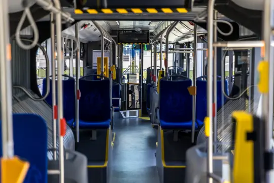 Wnętrze autobusu z niebieskimi siedzeniami i widokiem na przednią część pojazdu.