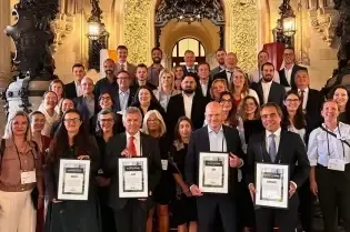 Grupa ludzi pozująca z certyfikatami w eleganckim wnętrzu.
