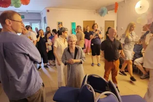 Grupa ludzi w różnym wieku bawi się w kolorowo udekorowanej sali.