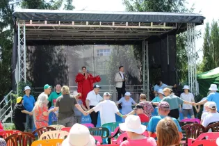 Występ artystyczny na scenie, publiczność tańczy w kręgu.